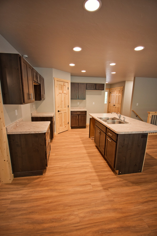 Eat-in kitchen - mid-sized rustic l-shaped medium tone wood floor and brown floor eat-in kitchen idea with a double-bowl sink, recessed-panel cabinets, dark wood cabinets, an island and gray countertops
