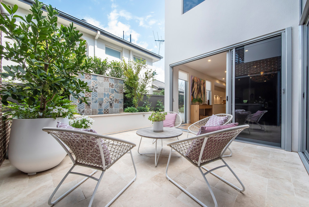 This is an example of an expansive beach style side yard patio in Melbourne with a water feature and natural stone pavers.