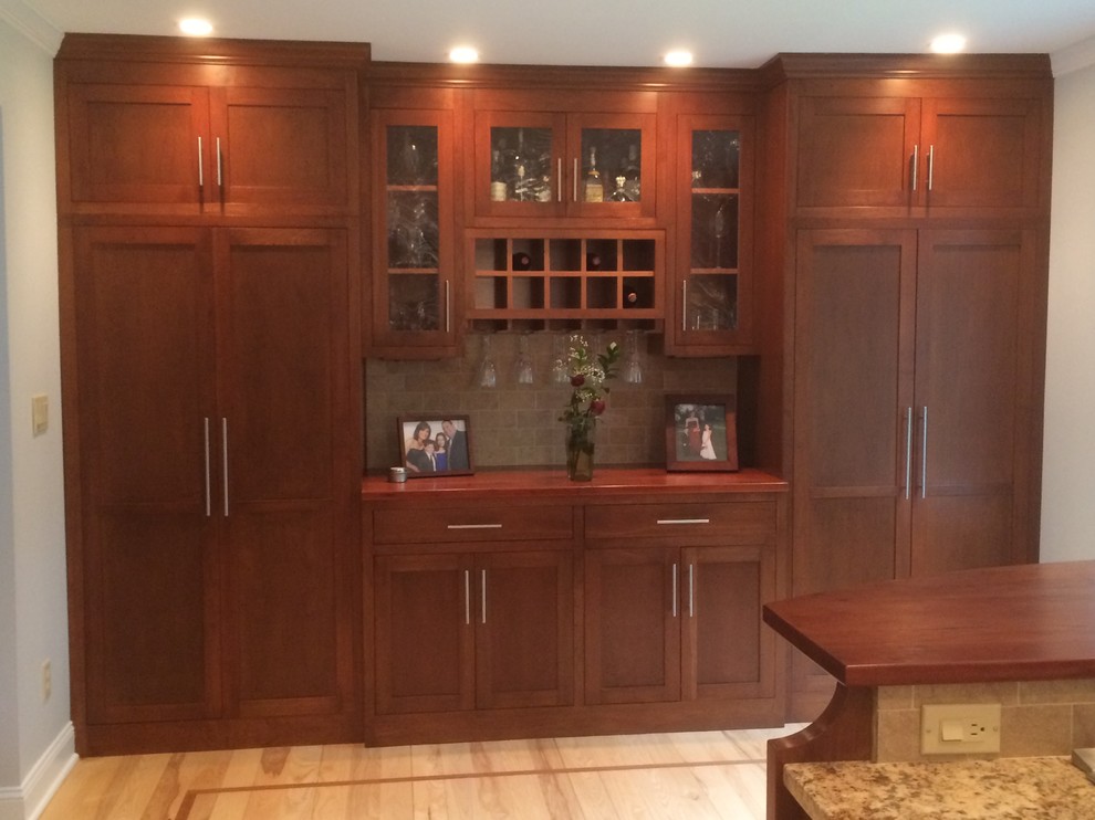 Large arts and crafts u-shaped seated home bar in Manchester with an undermount sink, flat-panel cabinets, dark wood cabinets, quartzite benchtops, beige splashback, marble splashback and light hardwood floors.