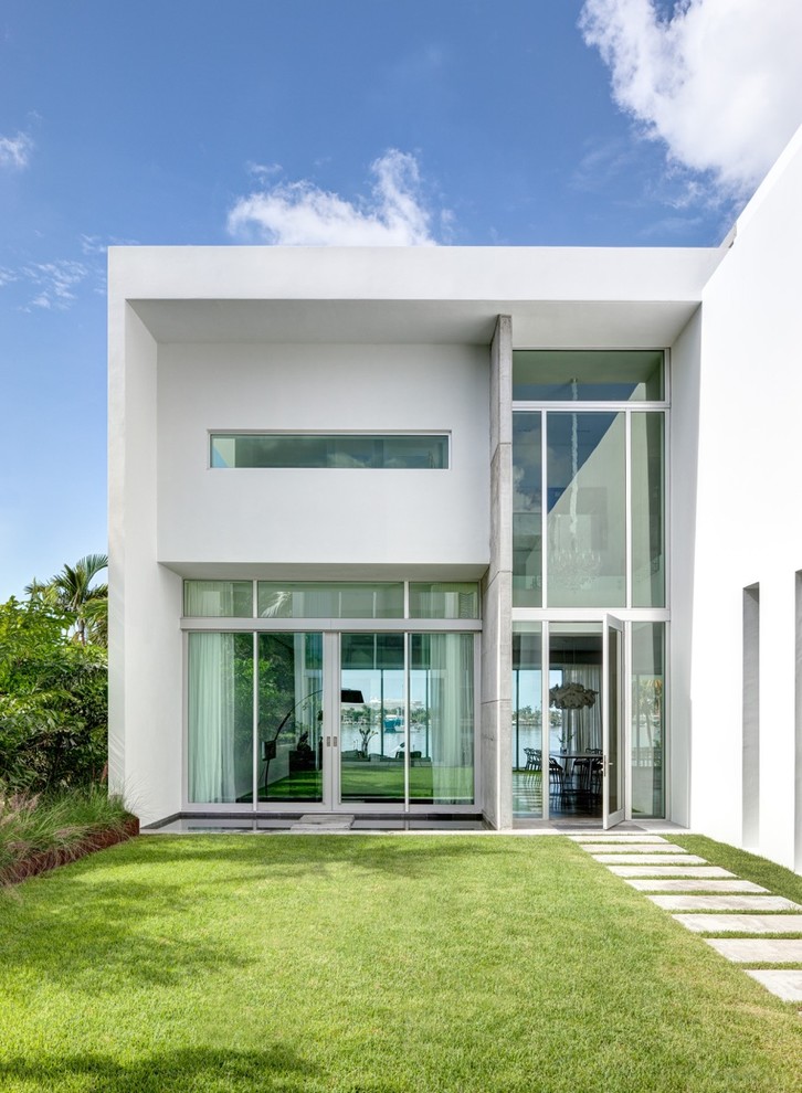 This is an example of a large modern two-storey concrete white house exterior in Miami with a flat roof and a mixed roof.
