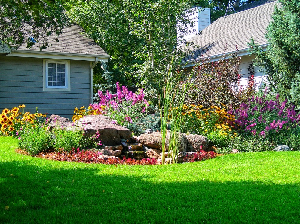 This is an example of a mid-sized traditional front yard partial sun garden in Other with a water feature and mulch.
