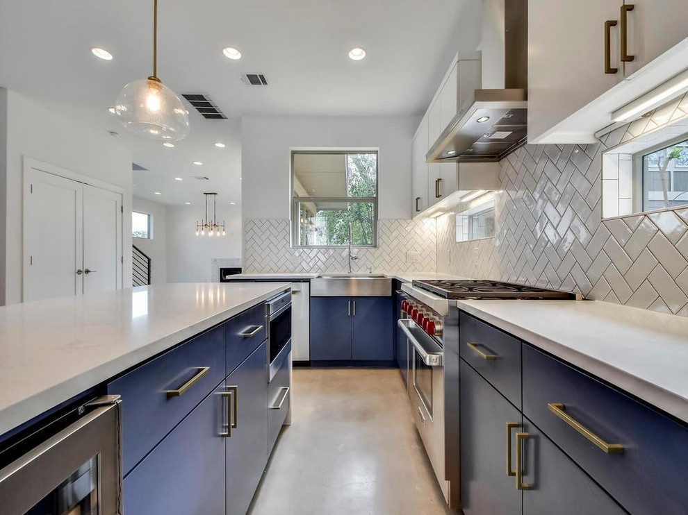 Inspiration for a mid-sized modern l-shaped open plan kitchen in Austin with a farmhouse sink, flat-panel cabinets, white cabinets, marble benchtops, grey splashback, porcelain splashback, stainless steel appliances, concrete floors, with island, grey floor and white benchtop.