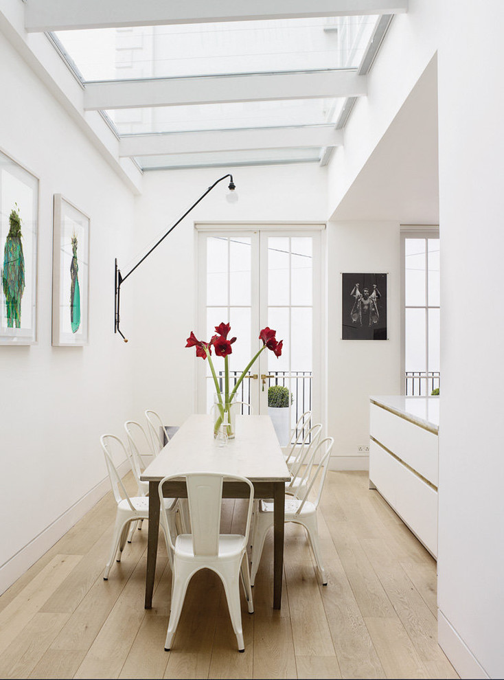Contemporary dining room in London with white walls and light hardwood floors.
