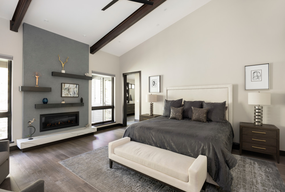Modernes Hauptschlafzimmer mit grauer Wandfarbe, braunem Holzboden, Kamin, Kaminumrandung aus Beton, grauem Boden und freigelegten Dachbalken in Denver