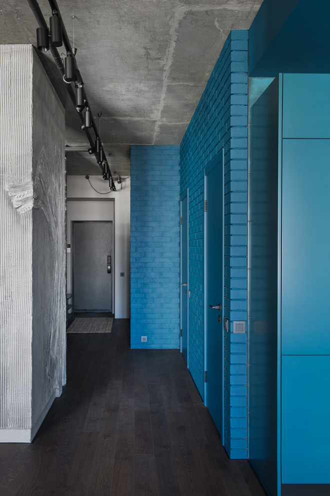 Immagine di un ingresso o corridoio industriale di medie dimensioni con pareti blu, parquet scuro, pavimento marrone e pareti in mattoni