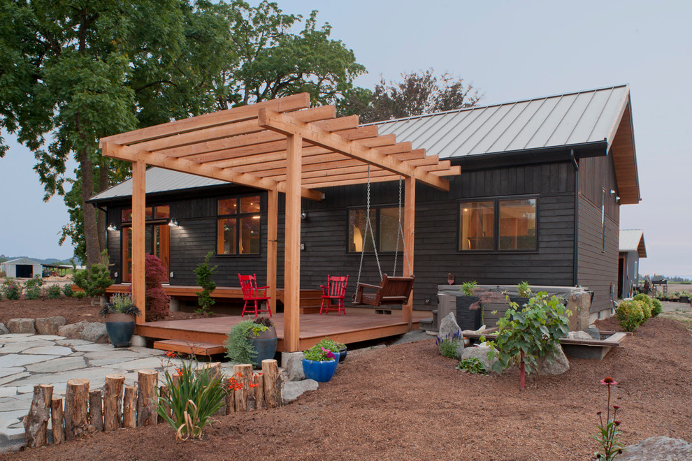 Small trendy stone back porch idea in New York with a pergola