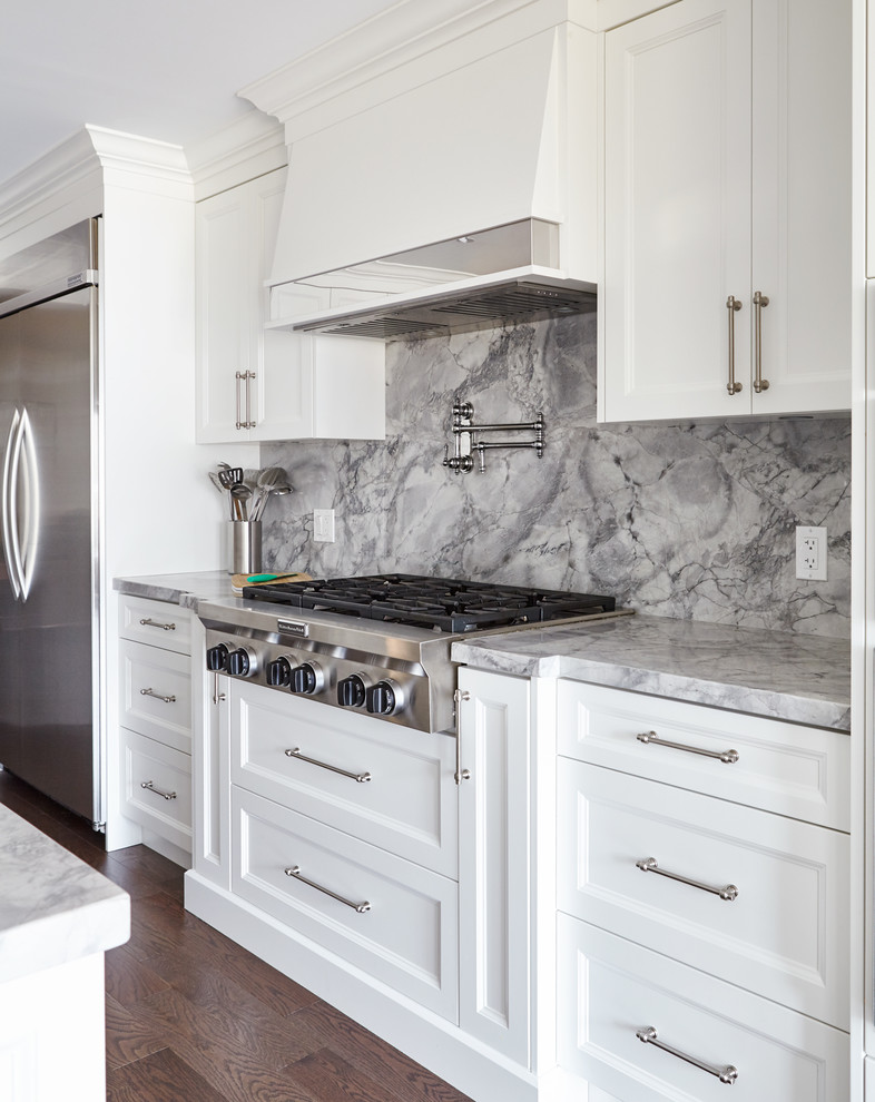 Open concept kitchen - mid-sized transitional single-wall medium tone wood floor open concept kitchen idea in Toronto with an undermount sink, beaded inset cabinets, white cabinets, marble countertops, gray backsplash, stone slab backsplash, stainless steel appliances and an island