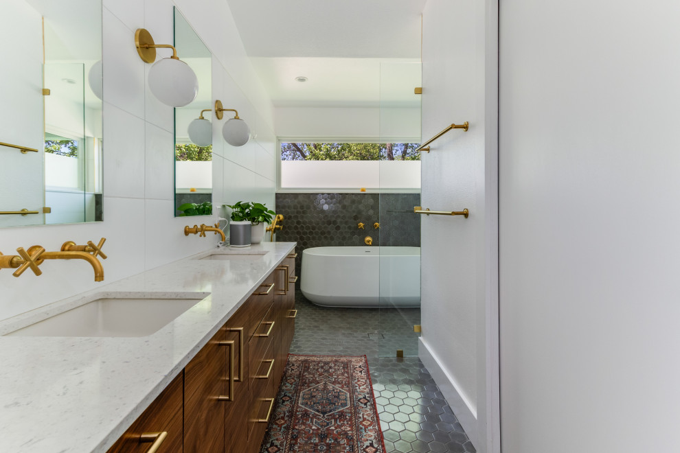 Midcentury bathroom in Austin with flat-panel cabinets, medium wood cabinets, a freestanding tub, gray tile, white walls, an undermount sink, grey floor, white benchtops, a double vanity and vaulted.