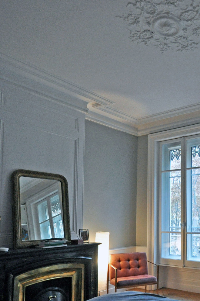 リヨンにある広いコンテンポラリースタイルのおしゃれな主寝室 (グレーの壁、標準型暖炉、石材の暖炉まわり、淡色無垢フローリング、ベージュの床、羽目板の壁)