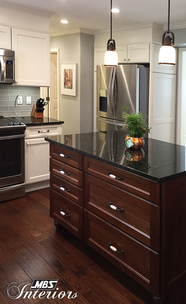Example of a mid-sized transitional l-shaped medium tone wood floor and brown floor eat-in kitchen design with an undermount sink, white cabinets, granite countertops, gray backsplash, subway tile backsplash, stainless steel appliances, an island and recessed-panel cabinets