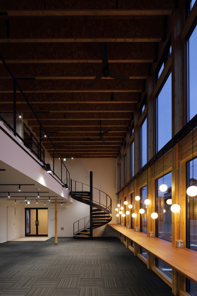 Geräumiges Industrial Arbeitszimmer mit Studio, weißer Wandfarbe, Teppichboden, freistehendem Schreibtisch, schwarzem Boden, freigelegten Dachbalken und Tapetenwänden in Sonstige