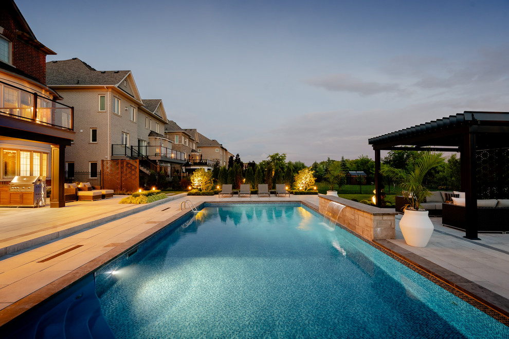 Large transitional backyard concrete paver and rectangular lap pool landscaping photo in Toronto