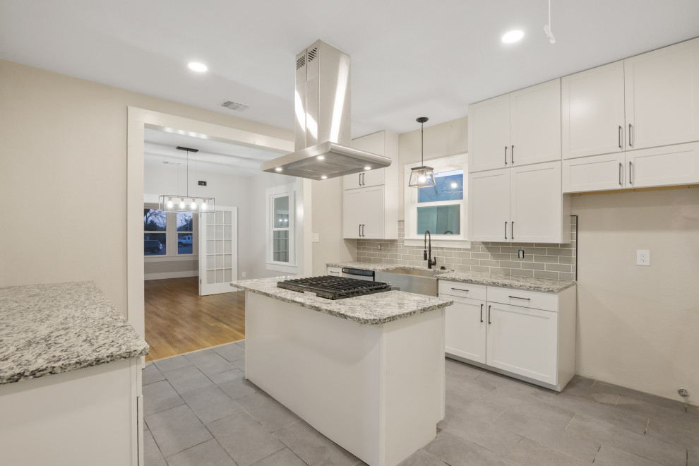 Large modern galley eat-in kitchen in Austin with an undermount sink, shaker cabinets, white cabinets, granite benchtops, grey splashback, ceramic splashback, stainless steel appliances, ceramic floors, with island, grey floor and multi-coloured benchtop.