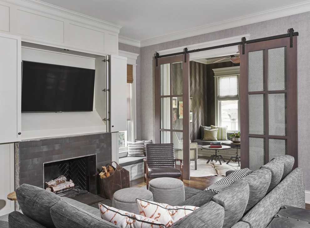 Example of a mid-sized trendy enclosed dark wood floor and brown floor family room design with gray walls, a standard fireplace, a brick fireplace and a wall-mounted tv