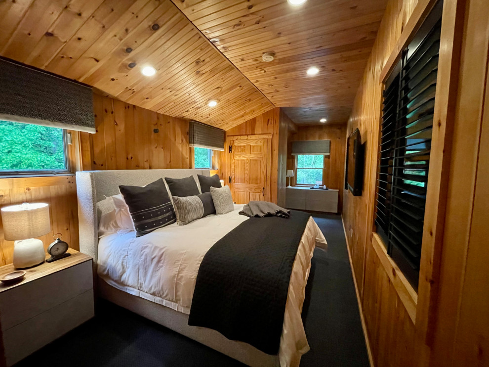 This is an example of a mid-sized guest bedroom in Boston with carpet, no fireplace, black floor, wood and panelled walls.
