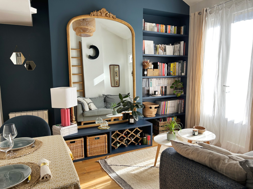 Photo of a small living room in Paris with blue walls and light hardwood floors.