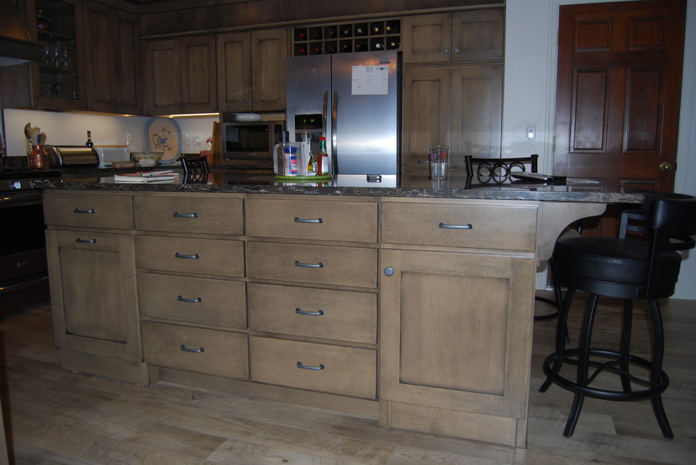 Inspiration for a large transitional u-shaped vinyl floor and brown floor eat-in kitchen remodel with recessed-panel cabinets, brown cabinets, black backsplash, stainless steel appliances, an island, quartz countertops and a double-bowl sink
