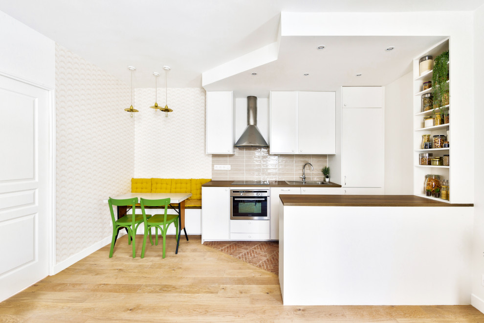 Design ideas for a mid-sized scandinavian galley open plan kitchen in Paris with an undermount sink, flat-panel cabinets, white cabinets, wood benchtops, pink splashback, ceramic splashback, stainless steel appliances, terra-cotta floors and with island.