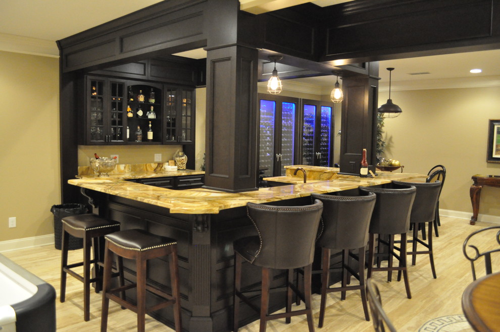 Design ideas for a large traditional u-shaped seated home bar in Atlanta with an undermount sink, raised-panel cabinets, dark wood cabinets, onyx benchtops, beige splashback and light hardwood floors.