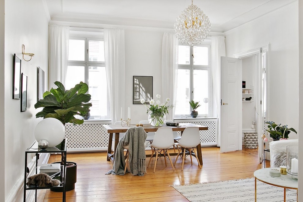 Traditional living room in Stockholm with white walls, medium hardwood floors and orange floor.