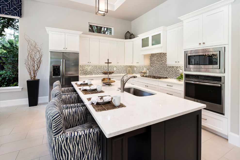 Transitional l-shaped porcelain tile kitchen photo in Miami with a single-bowl sink, shaker cabinets, white cabinets, quartzite countertops, multicolored backsplash, mosaic tile backsplash, stainless steel appliances and an island