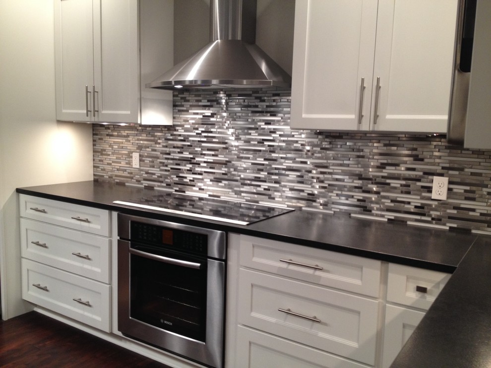 This is an example of a contemporary eat-in kitchen in Miami with metal splashback.