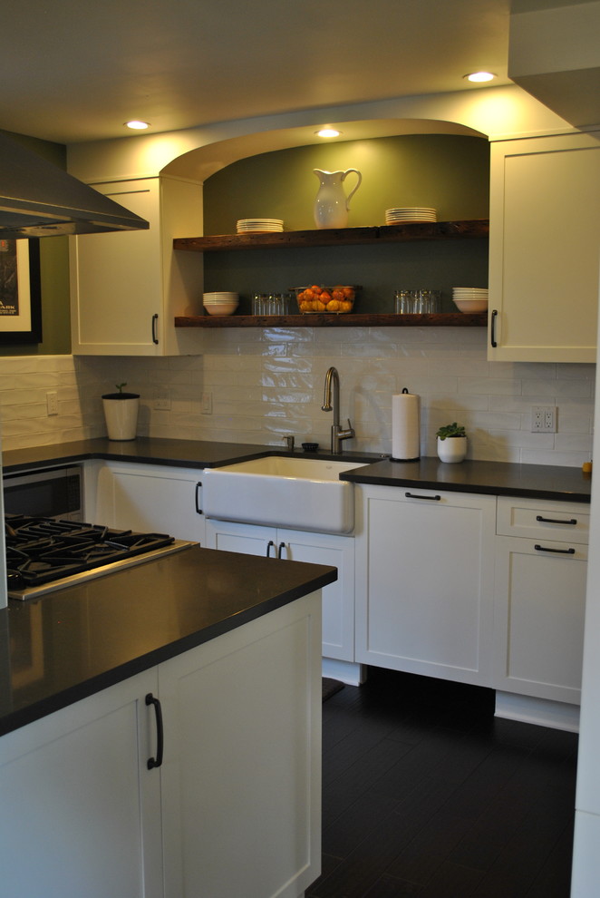 Kitchen - transitional dark wood floor kitchen idea with a farmhouse sink, recessed-panel cabinets, quartz countertops, white backsplash, ceramic backsplash and stainless steel appliances