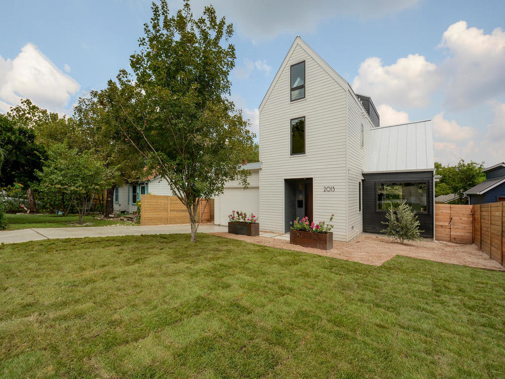 Large modern three-storey white exterior in Austin with a gable roof and vinyl siding.