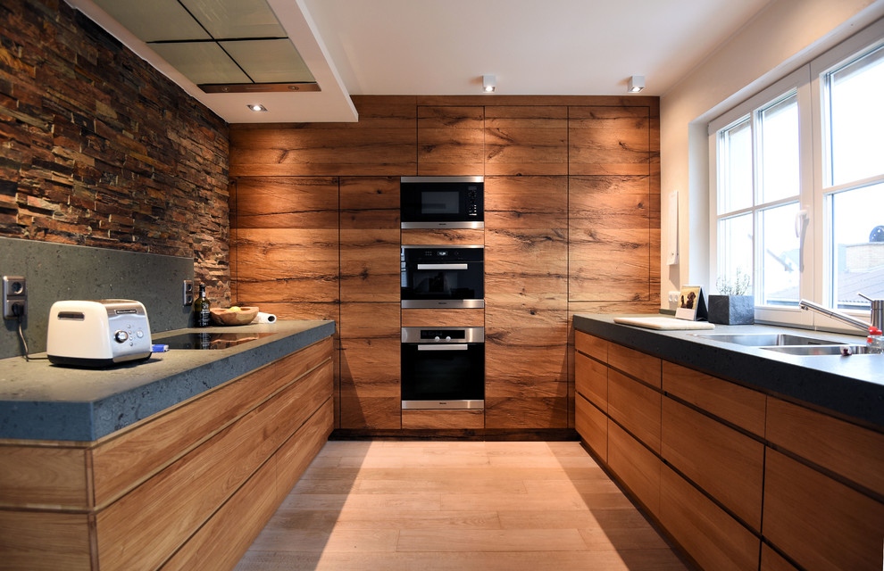 Inspiration for a mid-sized country u-shaped kitchen in Frankfurt with flat-panel cabinets, medium wood cabinets, granite benchtops, stone slab splashback, stainless steel appliances, light hardwood floors, no island, grey benchtop, a double-bowl sink, beige floor and multi-coloured splashback.