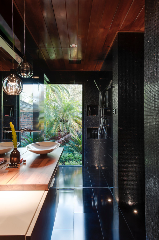 Design ideas for a small contemporary master bathroom in Sydney with a vessel sink, flat-panel cabinets, wood benchtops, a corner shower, a wall-mount toilet, black tile, mosaic tile and ceramic floors.