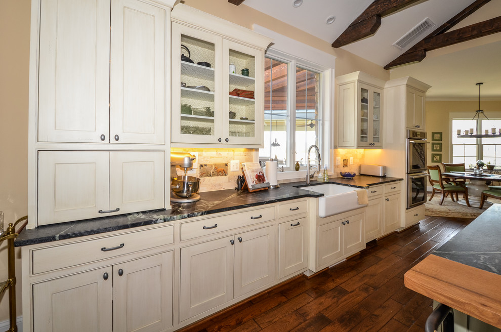 Design ideas for an expansive country open plan kitchen in DC Metro with a farmhouse sink, beaded inset cabinets, distressed cabinets, soapstone benchtops, beige splashback, ceramic splashback, stainless steel appliances, dark hardwood floors, with island and brown floor.