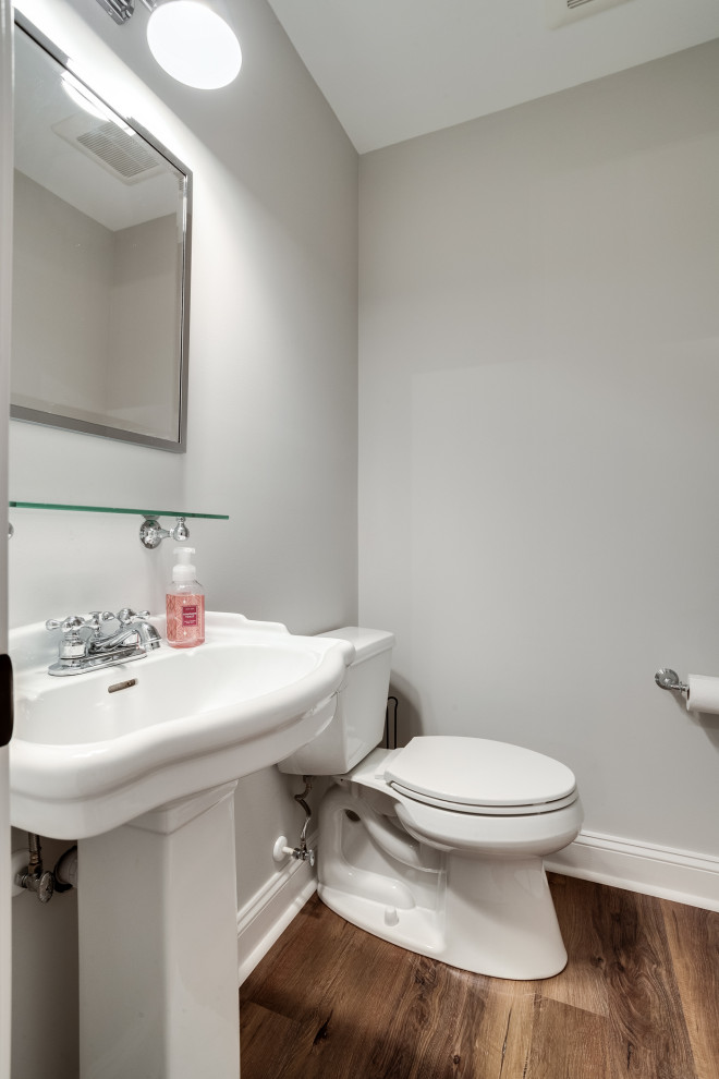 Photo of a small country 3/4 bathroom in Baltimore with open cabinets, white cabinets, a two-piece toilet, grey walls, laminate floors, a pedestal sink, brown floor and white benchtops.