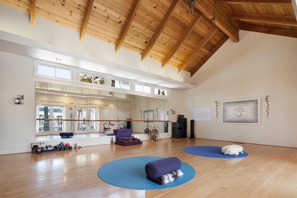 This is an example of a mediterranean multipurpose gym in Los Angeles with white walls, light hardwood floors and brown floor.