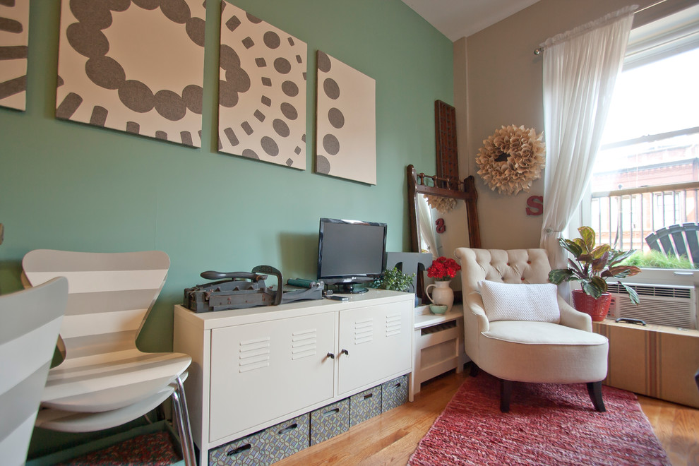 This is an example of a small eclectic living room in New York with green walls, medium hardwood floors and a freestanding tv.