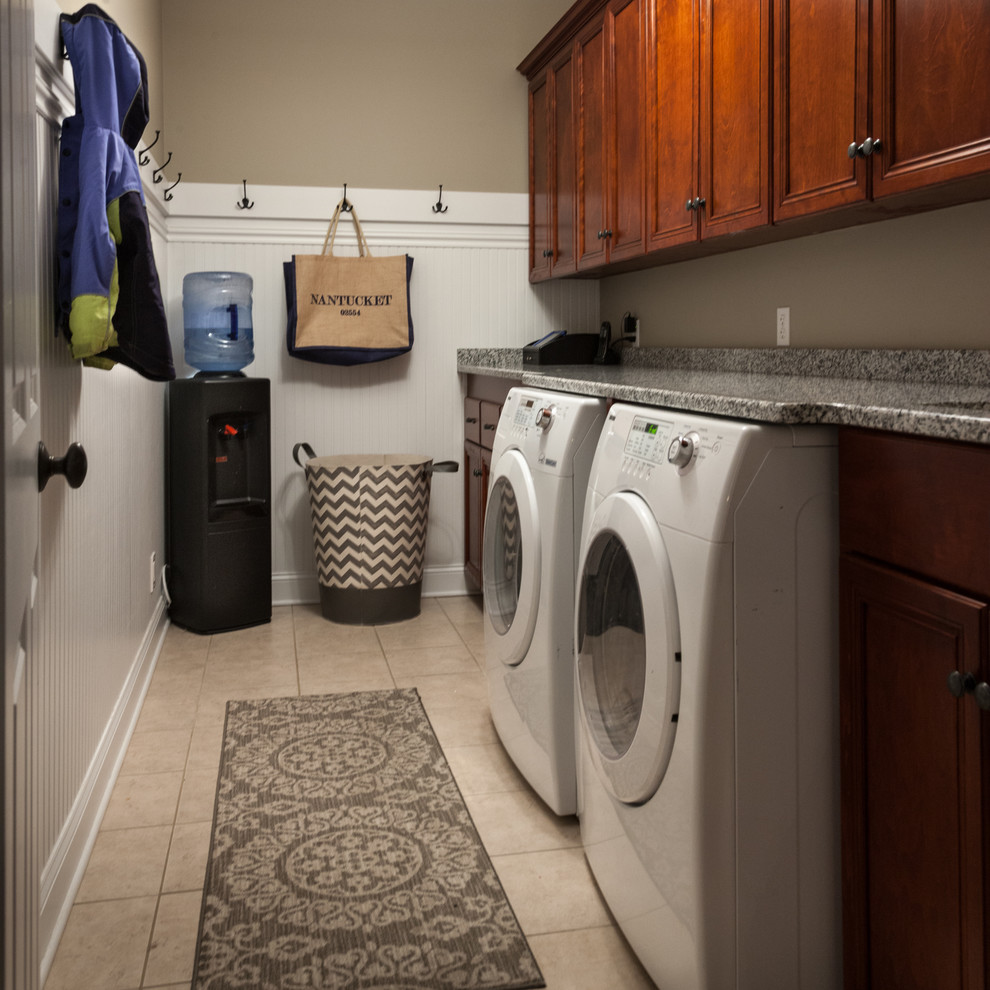 Inspiration for a mid-sized transitional galley utility room in Chicago with raised-panel cabinets, granite benchtops, grey walls, porcelain floors, a side-by-side washer and dryer, an undermount sink and dark wood cabinets.