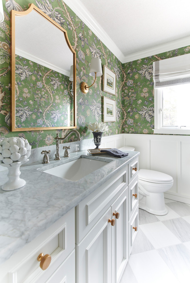 Inspiration for a timeless marble floor and wallpaper powder room remodel in New York with furniture-like cabinets, white cabinets, a one-piece toilet, an undermount sink, a built-in vanity, quartzite countertops and gray countertops
