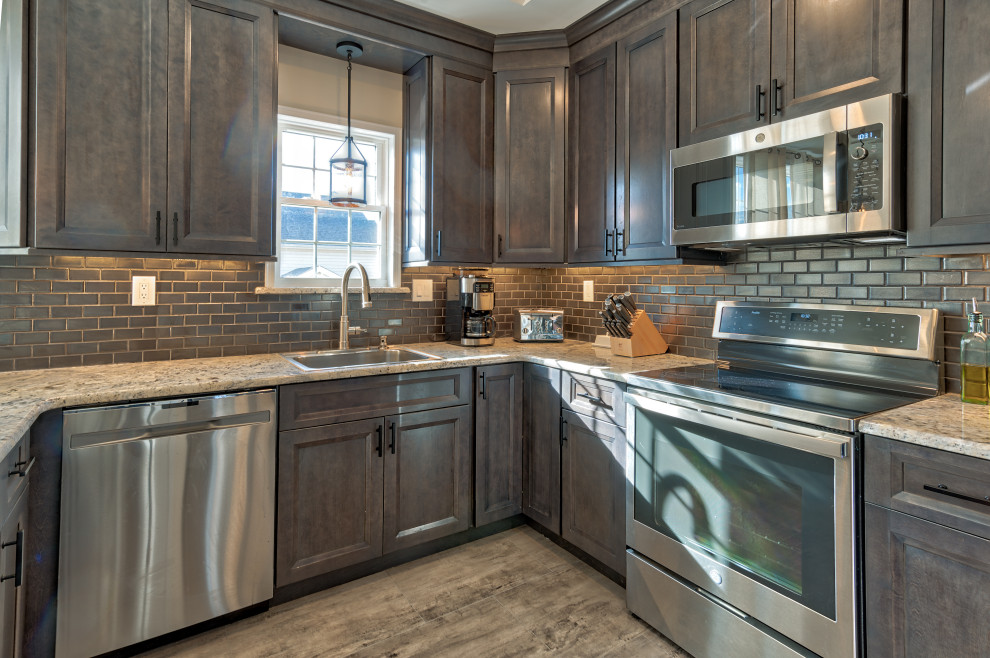 Photo of a classic u-shaped kitchen/diner in Philadelphia with a submerged sink, recessed-panel cabinets, grey cabinets, granite worktops, grey splashback, metro tiled splashback, stainless steel appliances, porcelain flooring, no island, brown floors, multicoloured worktops and a drop ceiling.