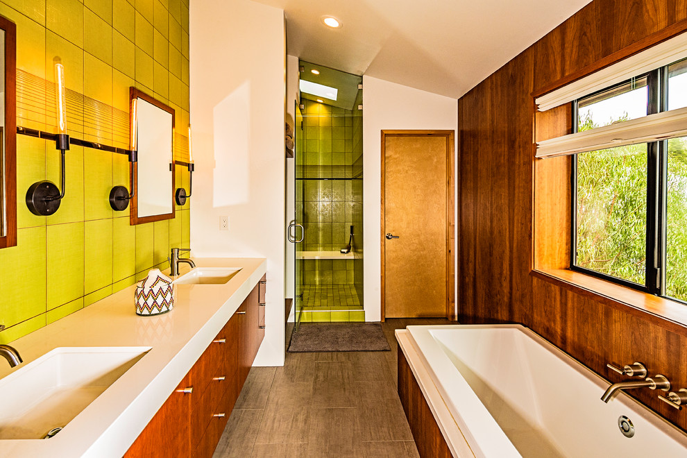 Mid-sized midcentury master bathroom in San Diego with flat-panel cabinets, medium wood cabinets, a drop-in tub, an alcove shower, a one-piece toilet, green tile, ceramic tile, brown walls, ceramic floors, an integrated sink, engineered quartz benchtops, grey floor, a hinged shower door and white benchtops.