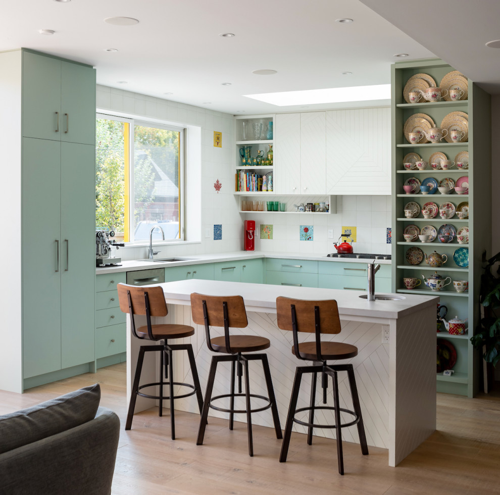 Photo of a large transitional u-shaped kitchen pantry in Toronto with a double-bowl sink, flat-panel cabinets, green cabinets, concrete benchtops, white splashback, ceramic splashback, stainless steel appliances, medium hardwood floors, with island, brown floor and grey benchtop.