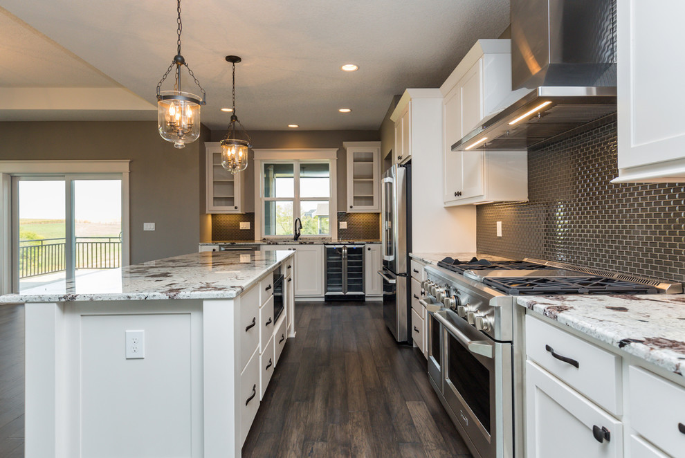 Inspiration for a transitional l-shaped dark wood floor and brown floor kitchen remodel with an undermount sink, shaker cabinets, white cabinets, granite countertops, gray backsplash, glass sheet backsplash, stainless steel appliances, an island and white countertops