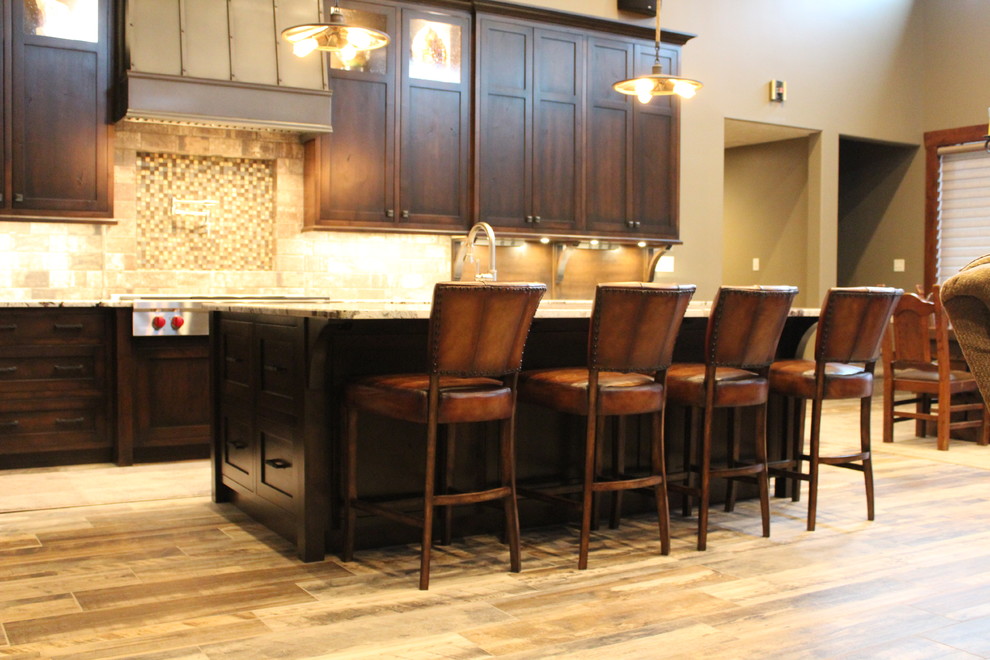 Photo of a large traditional l-shaped eat-in kitchen in St Louis with a farmhouse sink, shaker cabinets, dark wood cabinets, granite benchtops, ceramic splashback, panelled appliances and with island.