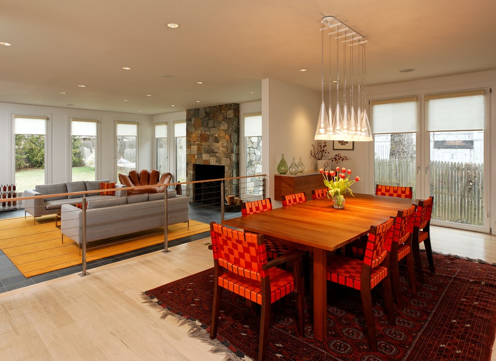 Inspiration for a mid-sized contemporary open plan dining in DC Metro with white walls, light hardwood floors, beige floor, a two-sided fireplace and a wood fireplace surround.