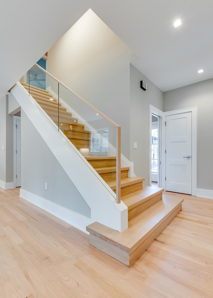 Photo of a mid-sized transitional wood straight staircase in DC Metro with wood risers and glass railing.