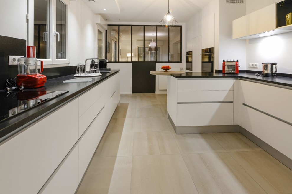 Design ideas for a large transitional galley separate kitchen in Angers with an undermount sink, flat-panel cabinets, white cabinets, granite benchtops, black splashback, black appliances, ceramic floors, a peninsula, beige floor and black benchtop.