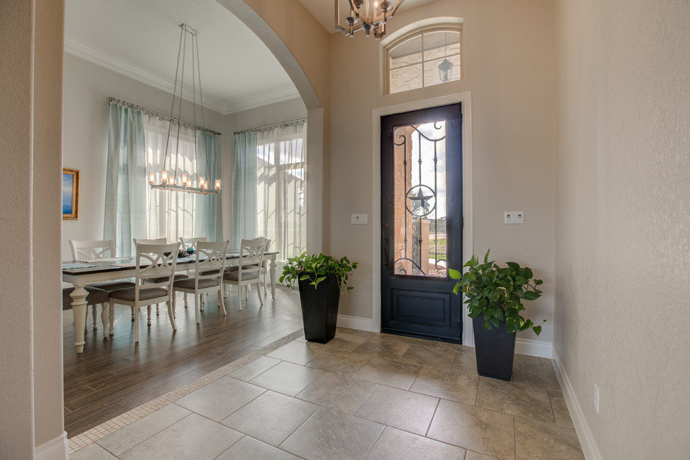 Photo of a mid-sized entry hall in Austin with beige walls, ceramic floors, a glass front door and brown floor.
