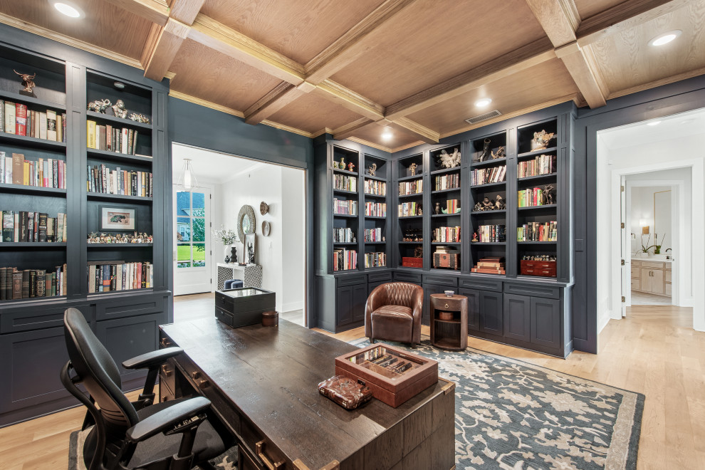 Design ideas for a large transitional home office in Dallas with a library, blue walls, light hardwood floors, a standard fireplace, a wood fireplace surround, a freestanding desk, coffered and panelled walls.