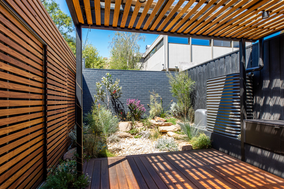 This is an example of a small and australian native courtyard partial sun xeriscape for summer in Melbourne with with rock feature and decking.