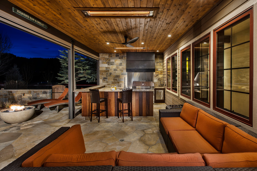 Inspiration for a mid-sized arts and crafts backyard patio in Denver with a fire feature, natural stone pavers and a roof extension.