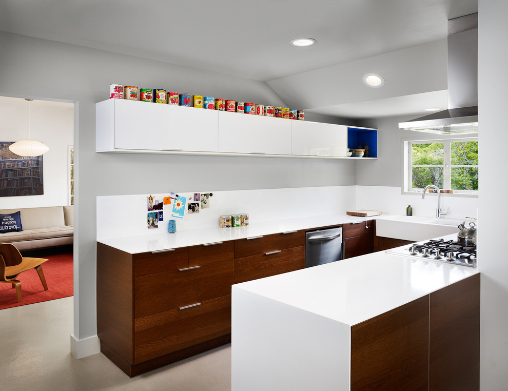 This is an example of a contemporary u-shaped kitchen in Austin with a farmhouse sink, stainless steel appliances, flat-panel cabinets and dark wood cabinets.