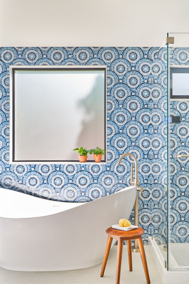 Exempel på ett mellanstort modernt en-suite badrum, med ett fristående badkar, en hörndusch, blå kakel, glaskakel, blå väggar och dusch med gångjärnsdörr